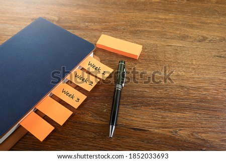 Notebook with weekly page marker an pen on wooden table 