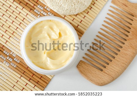 Yellow facial mask (banana face cream, shea butter hair mask, body butter) in the small white container. Natural skin and hair concept. Top view, copy space. Royalty-Free Stock Photo #1852035223