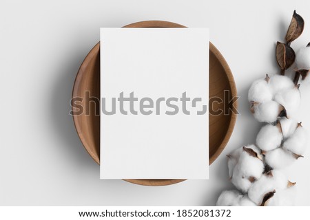 White invitation card mockup on a wooden plate with a dried cotton branch. 5x7 ratio, similar to A6, A5.