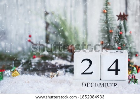 Christmas Eve. White wood calendar blocks with the date December 24th and Christmas decorations with snow. Selective focus with blurred background. 