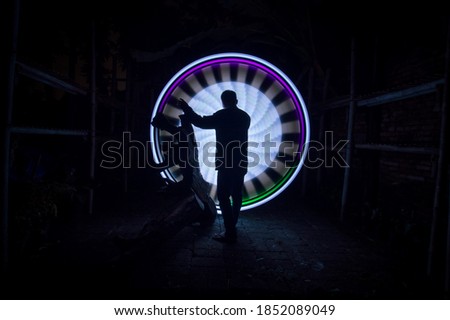 One person standing alone against a purple and white circle light painting as the backdrop
