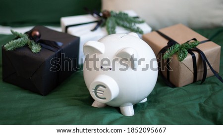 White piggy bank with stylish christmas and new year gift boxes. Symbol of euro on a piglet. Saving money for presents, bank deposits and credits concept. Selective focus.