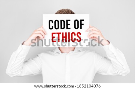 Man covers his face with a white paper with text CODE OF ETHICS