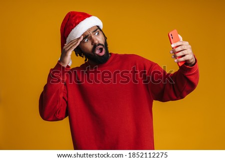 Shocked african american guy taking selfie on cellphone isolated over yellow wall