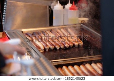 Sizziling Sausages cooking on a steel hot plate at a Christmas Market stall, Harrogate, North Yorkshire, UK. 