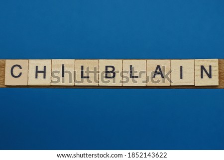 gray word chilblain in small square wooden letters with black font on a blue background