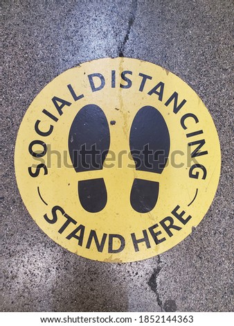 social distance floor sign yellow and black in color