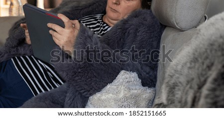Woman in a rabbit fur jacket works with a tablet PC in the home office