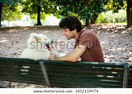 Interesting man sitting with his dog on the chair in the park enjoying a wonderful day