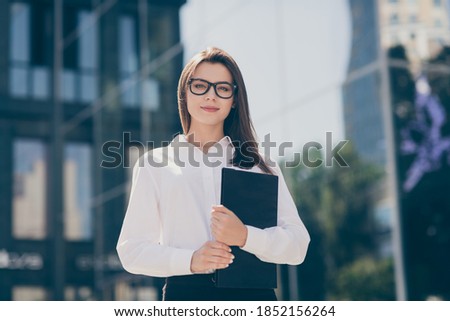 Photo of adorable charming young lady dressed white formal shirt arm glasses holding clipboard outside
