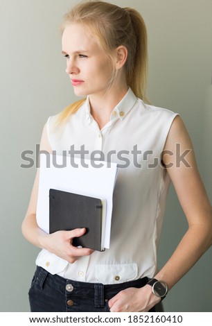 Confident business woman holding a notebook and documents.
