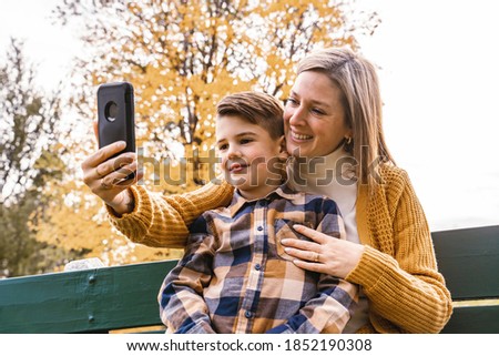 family mother taking selfie by smartphone in autumn park