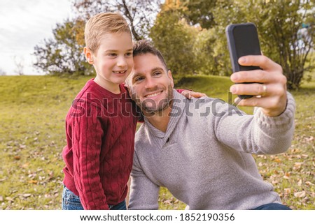 family father taking selfie by smartphone in autumn park
