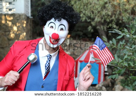 Spooky clown holding flag and microphone