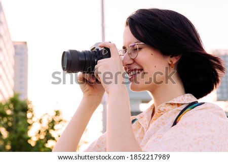 beautiful traveler woman smiling and taking a photo with a vintage camera, concept of youth and creative lifestyle, copy space for text
