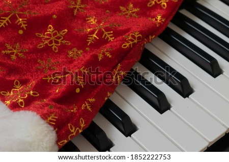 Piano keyboard. Musical background. Piano with santa hat.