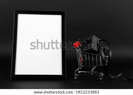 A frame and shopping cart with gifts on a black background, a blank for the design, concept. Copy space.