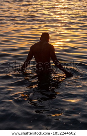 Man from Cuba into the water during the sunrise.  Some picks with a blue and yellow tones