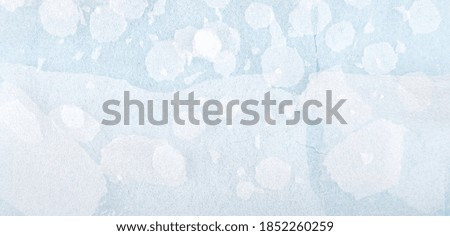 White round plastic foam sheet pieces on blue background. Winter snowfall concept. Torn foam polyethylene transparent pieces as snowflakes.