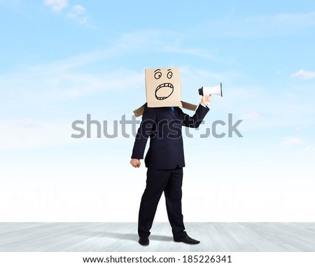 Businessman wearing carton box on head and screaming in to megaphone