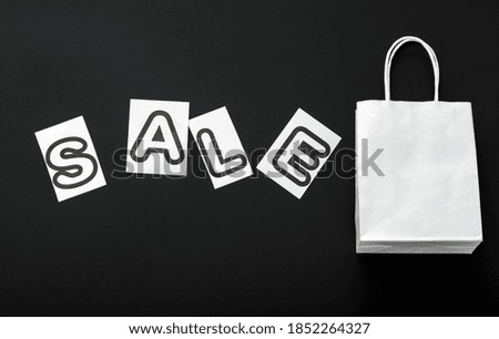 Sale text with white shopping paper bag on black background. Delivery mock up black on white craft paper bag package. Sale promotion discount.