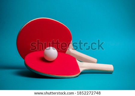 Table tennis or ping pong rackets and ball on the blue table. Background, shallow DOF.