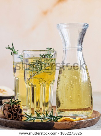 Pear or apple cider in glasses and bottle with rosemary, cinnamon and fresh organic pears. Fermented fruit drink. Light concrete background. Selective focus.