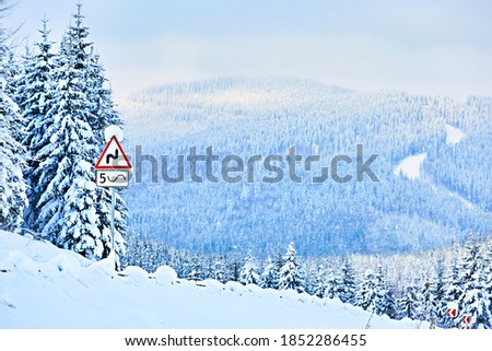 Winter landscape in the mountains with a road sign. The road is covered with snow