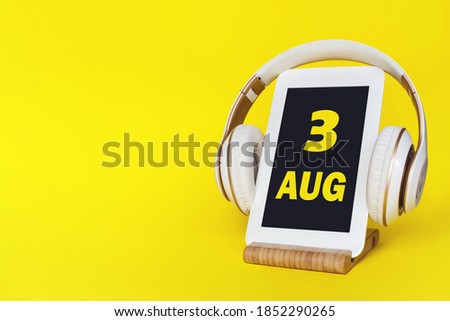August 3rd. Day 3 of month, Calendar date. Stylish headphones and modern tablet on yellow background. Space for text. Education, technology, lifestyle. Summer month, day of the year concept