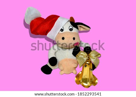On a pink background, the symbol of 2021 Chinese new year is a soft toy cow with a Golden bell.