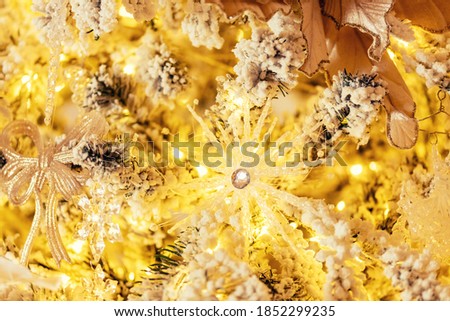 Closeup decorated white Christmas tree on yellow lights blurred background.