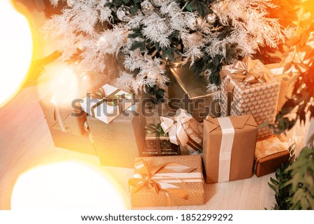 Bokeh sun illuminated in background gifts boxes under Christmas tree in interior, top view.