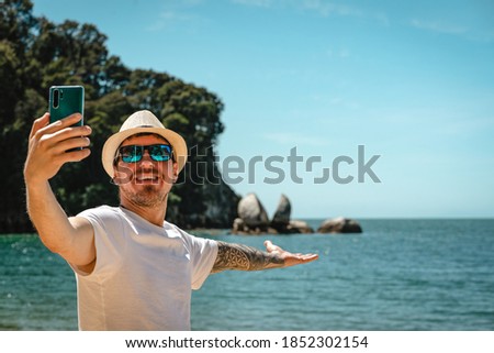 Caucasian man taking a selfie with smartphone in Split Apple Rock, Abel Tasman National Park, New Zealand.