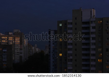 The dark blue sky and the windows of multi-storey houses light up, the view of the street in the big city, going far away. Typical architecture in Kyiv, Ukraine