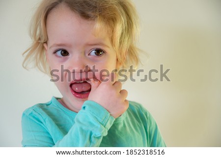 Portrait of cute blonde girl showing her teeth.