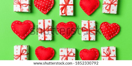 Composition of holiday white gift boxes and red textile hearts on colorful background. Valentine's day concept.