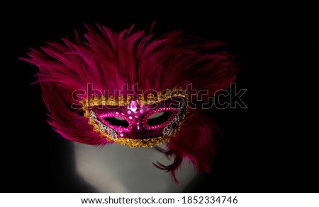 Venetian mask on mirrored surface with blurred background, selective focus.