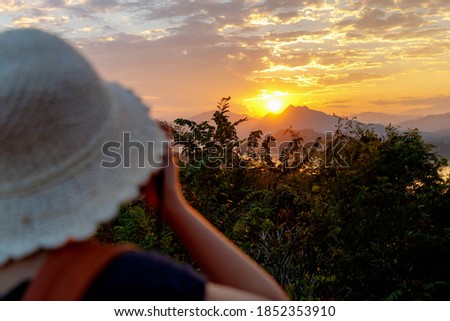 Phousi hill accessible by hiking, This summit with sweeping views is a well-known spot to watch sunset, Blurred tourist women taking picture while the sun goes down in the evening, Luang Prabang, Laos