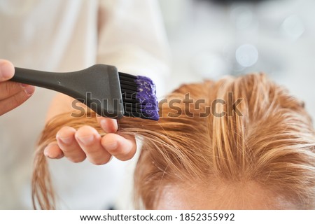Closeup man hands dyeing hair while using a black brush. Colouring of white hair at salon. Beauty care, hairstyling, fashion, lifestyle glamour concept Royalty-Free Stock Photo #1852355992