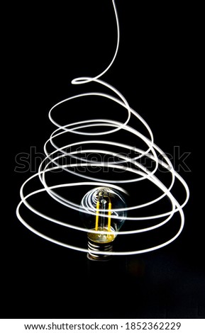 An abstract photo of light painting. A light bulb surrounded by neon lines of streaks of light Royalty-Free Stock Photo #1852362229