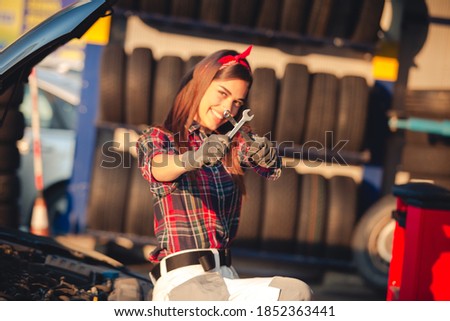 Girl mechanic ar repair shop doing maintenance on car engine