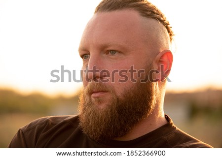 Hipster style bearded man. the attractive man the blonde with long hair of the European appearance with a beard. Man in t-shirt. portrait of a man. background of the field