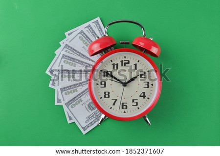 Alarm clock and stacks of banknotes on a green background. Business concept. 