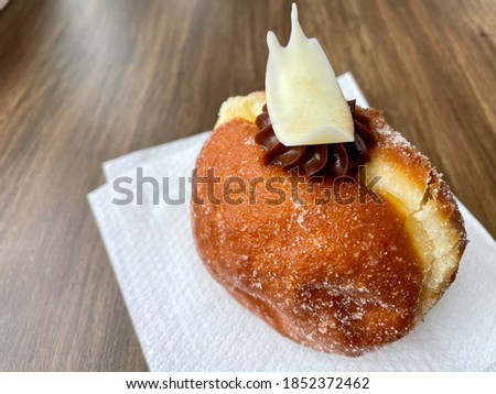 Filled doughnuts decorated with meringue and chocolate served on a napkin