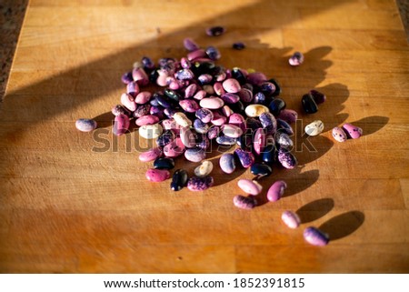 Pile of heirloom scarlet runner beans on blond wooden cutting board