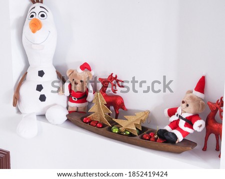 Christmas decorations of fir tree, deer, teddy bears, ball over white wall. 
