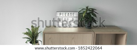 Please wear a mask business sign banner. Coronavirus prevention restriction notice at entrance. Mandatory facial covering wear inside store panoramic.