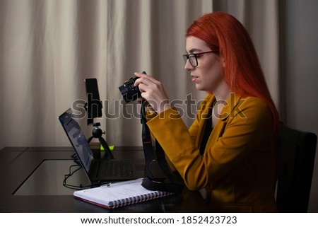 Woman working at home and reviewing the photos she has on her camera
