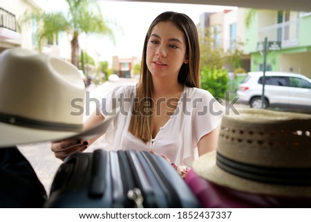 The young woman is packing her bags in the van because she is going on a trip.
