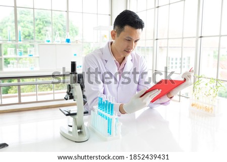 young man scientist reading a book sitting in laboratory